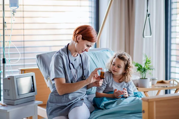 Friendly female doctor examining small girl in bed in hospital. — ストック写真