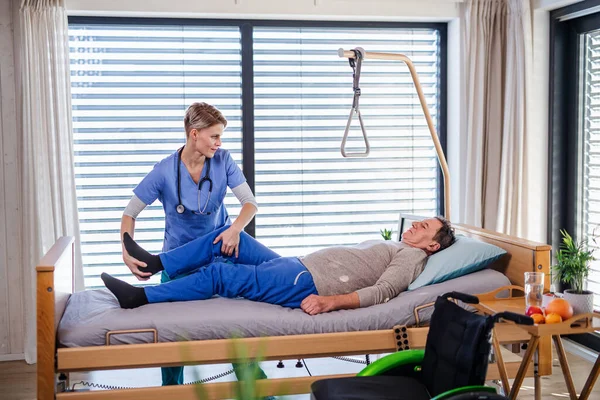 Um profissional de saúde e paciente idoso no hospital, fisioterapia . — Fotografia de Stock