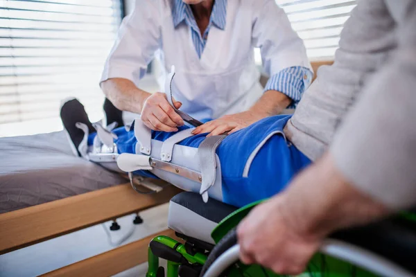 Oigenkännlig vårdpersonal och förlamad äldre patient på sjukhus. — Stockfoto