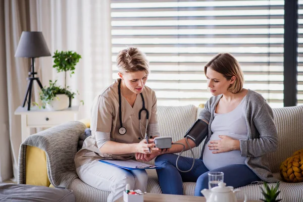 Eine Krankenschwester untersucht schwangere Frau zu Hause. — Stockfoto