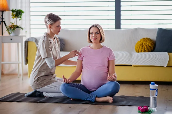 Schwangere macht Yoga-Übung mit Trainer zu Hause. — Stockfoto