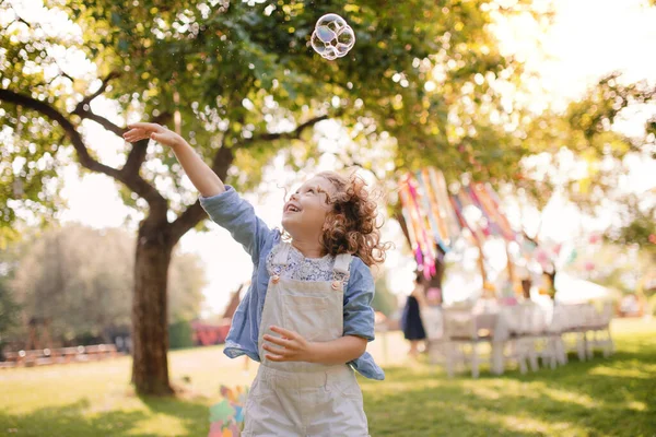 Портрет маленької дівчинки, що грає з бульбашками на відкритому повітрі на садовій вечірці влітку . — стокове фото