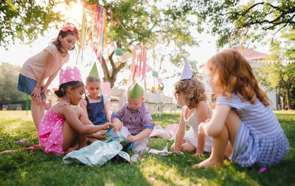 Síndrome de Down niño con amigos en fiesta de cumpleaños al aire libre en el jardín . — Foto de Stock