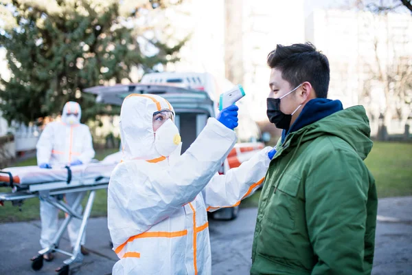 Personas con trajes de protección ayudando al hombre al aire libre, concepto coronavirus . —  Fotos de Stock