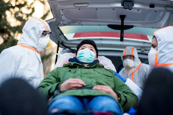 Menschen mit Schutzanzügen helfen Menschen im Freien, Coronavirus-Konzept. — Stockfoto