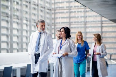 Bir grup doktor tıp konferansında koridorda yürüyor..