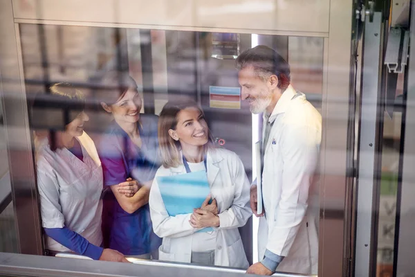 Grupp av läkare i hiss på medicinsk konferens, talar. — Stockfoto