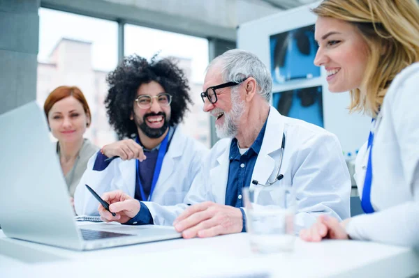 Groupe de médecins avec ordinateur portable sur conférence, équipe médicale discutant des questions . — Photo