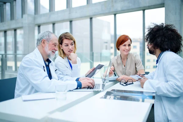 Groupe de médecins avec ordinateur portable sur conférence, équipe médicale discutant des questions . — Photo