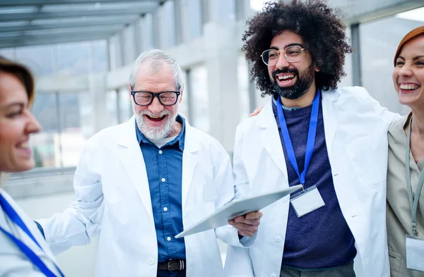 Groupe de médecins avec tablette sur conférence, équipe médicale riant . — Photo