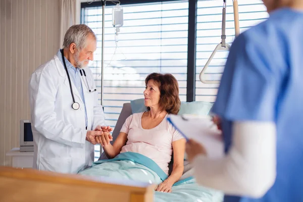 Arts en verpleegkundige onderzoeken senior patiënt in bed in het ziekenhuis. — Stockfoto