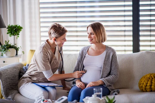 Un travailleur de la santé examine une femme enceinte à l'intérieur à la maison . — Photo