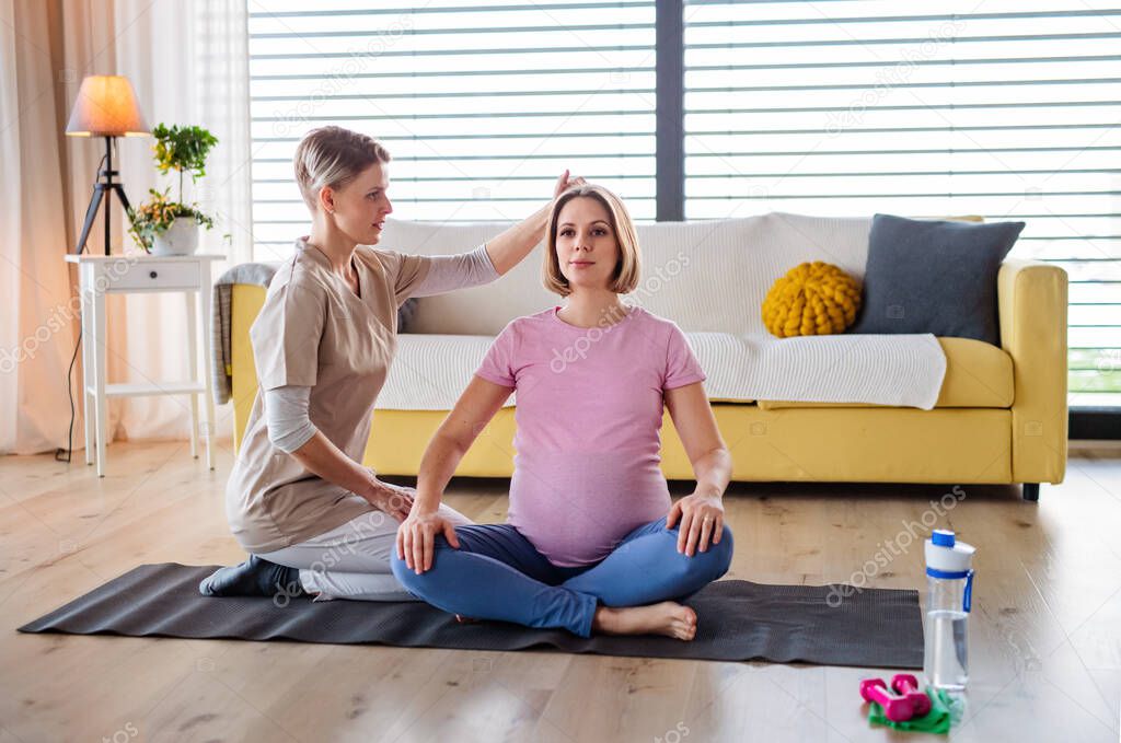 Pregnant woman doing yoga exercise with instructor at home.