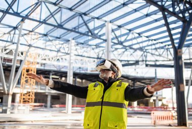 Man engineer using VR goggles on construction site.