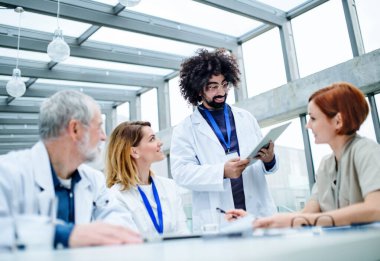 Konferansta tabletli bir grup doktor, tıbbi ekip sorunları tartışıyor.
