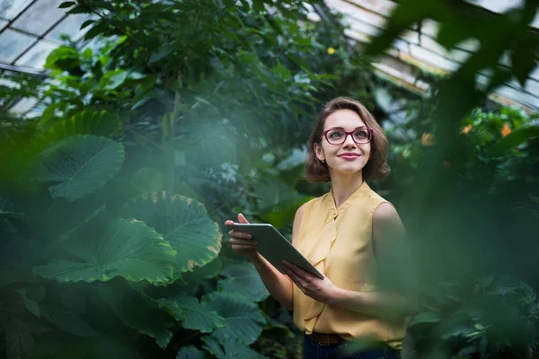Mujer joven con tableta de pie en el jardín botánico. Copiar espacio . — Foto de Stock