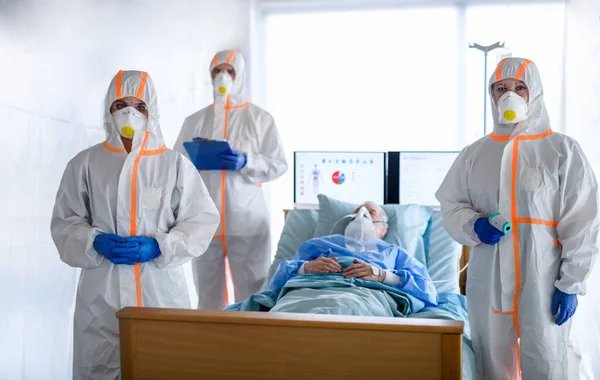 Doctors and infected patient in quarantine lying in bed in hospital, coronavirus concept. — Stock Photo, Image