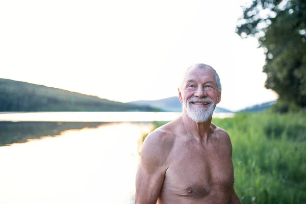 Senior pria berpakaian renang berdiri di tepi danau luar sebelum berenang . — Stok Foto