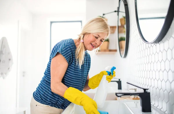 Старшая женщина в перчатках уборка ванной комнаты в помещении дома . — стоковое фото