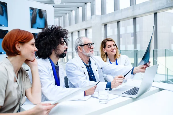 Ärztegruppe betrachtet Röntgenbild auf medizinischer Konferenz und diskutiert Fragen. — Stockfoto