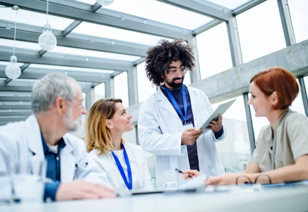 Ärztegruppe mit Tablet auf Konferenz, medizinisches Team diskutiert Fragen. — Stockfoto