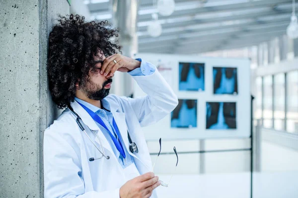 Znepokojený a unavený lékař stojící v nemocnici, koncepce koronového viru. — Stock fotografie