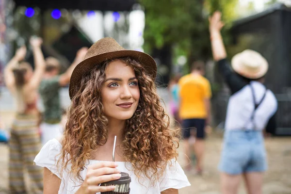 Beautiful young girl at summer festival, holding drink. — Stock Photo, Image