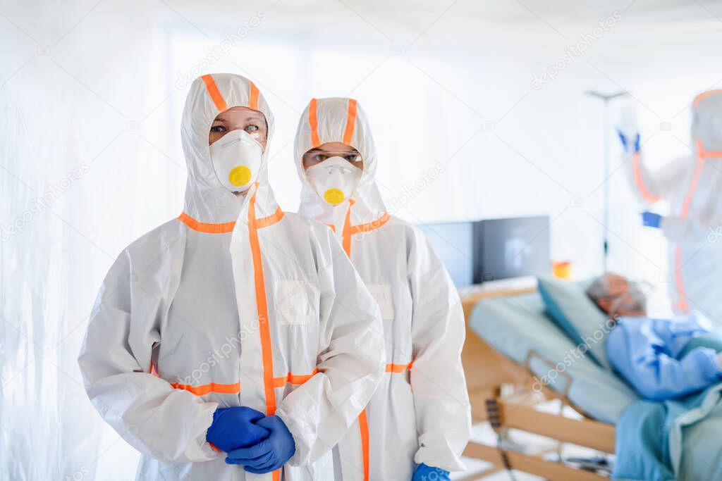 Doctors and infected patient in quarantine lying in bed in hospital, coronavirus concept.