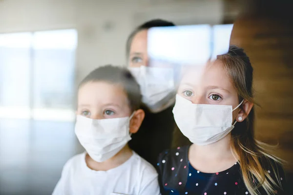 집안에서 마스크를 쓰고 있는 어머니와 아이들, 코로나 바이러스, 격리 개념. — 스톡 사진