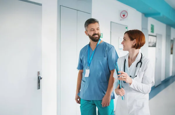 Portrait of man and woman doctor walking in hospital, talking. — Stock Photo, Image