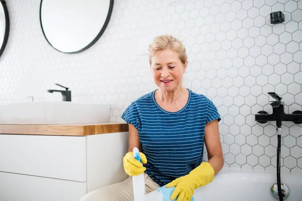 Senior woman with gloves cleaning bathroom indoors at home. — Stock Photo, Image