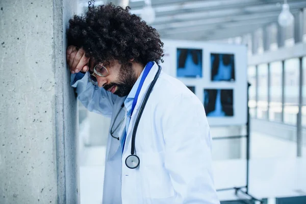 Znepokojený a unavený lékař stojící v nemocnici, koncepce koronového viru. — Stock fotografie