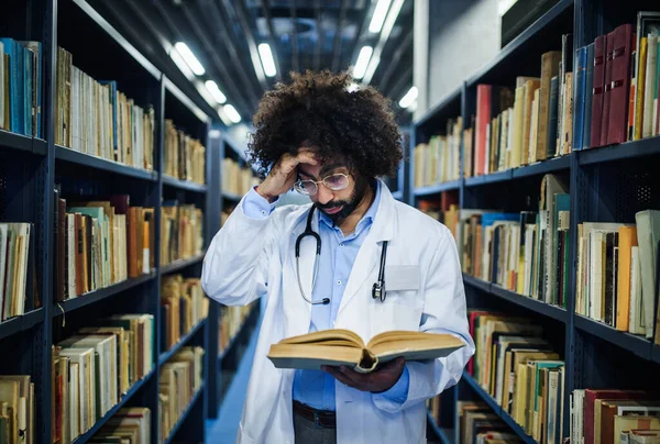 Médico de pie en la biblioteca, estudiando información sobre el virus corona . —  Fotos de Stock