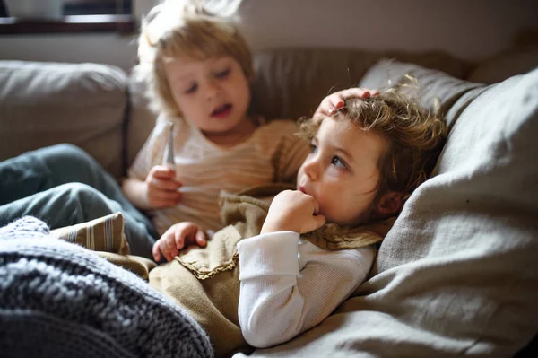 Dos pequeños niños enfermos hermano y hermana en casa acostados en la cama . —  Fotos de Stock