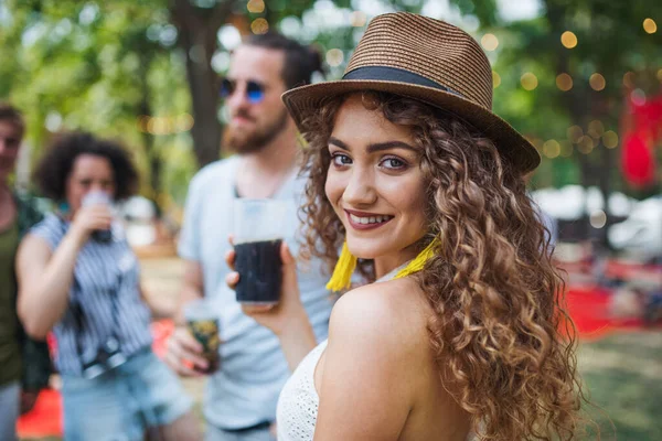 Piękna młoda dziewczyna z drinkiem stojąca na letnim festiwalu. — Zdjęcie stockowe