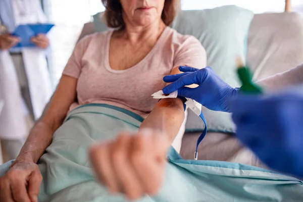 Asistentă medicală nerecunoscută cu pacient în pat în spital, luând sânge . — Fotografie, imagine de stoc