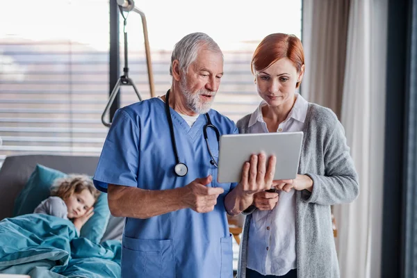 Doctor with tablet talking to mother of small hospitalized girl in hospital. — Stock Photo, Image