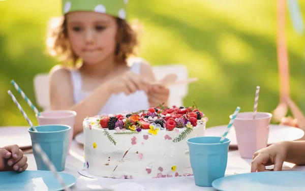 Niña con pastel celebrando cumpleaños al aire libre en el jardín en verano, concepto de fiesta . — Foto de Stock