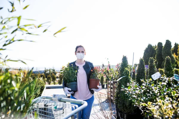 Mujer joven con máscaras faciales al aire libre compras en el centro de jardín, concepto de virus Corona . — Foto de Stock