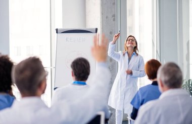 Bir grup doktor konferansta, tıbbi ekip oturuyor ve sunumu dinliyor..