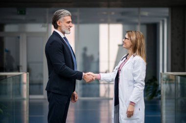 Doktor ilaç satış temsilcisiyle konuşuyor, el sıkışıyor..