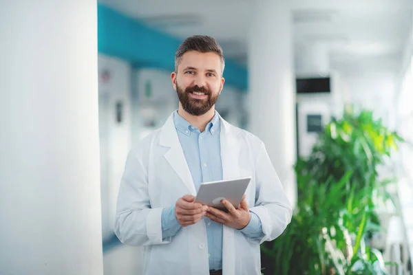 Portret lekarza stojącego w szpitalu, stosującego tabletkę. — Zdjęcie stockowe