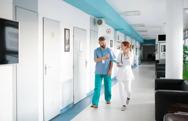 Portret mężczyzny i kobiety lekarz spacerujący po szpitalu, mówiący. — Zdjęcie stockowe