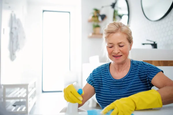 Senior woman with gloves cleaning bathroom indoors at home. — Stock Photo, Image