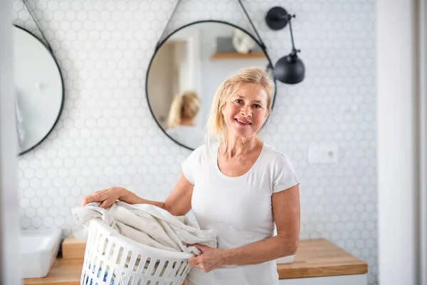 Retrato de mujer mayor con cesta de ropa interior en casa . — Foto de Stock