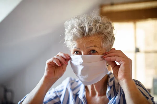 Старшая женщина в маске для лица дома, коронный вирус и карантин . — стоковое фото