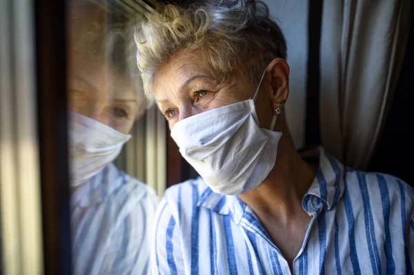 Femme âgée avec masque facial à l'intérieur à la maison, virus corona et concept de quarantaine . — Photo