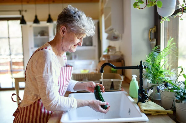 Kvinna tvätta grönsaker inomhus vid matlagning, corona virus koncept. — Stockfoto