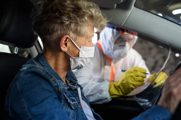 Luarea probei de test a virusului corona a femeii în vârstă în mașină, conceptul de carantină . — Fotografie, imagine de stoc
