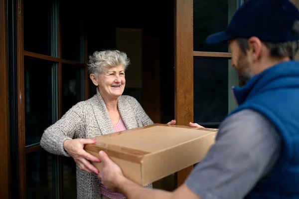 Courier delivering parcel to senior woman, corona virus and quarantine concept. — Stock Photo, Image
